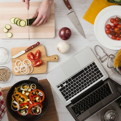 Man cooking in the kitchen and slicing vegetables on a chopping board, top view