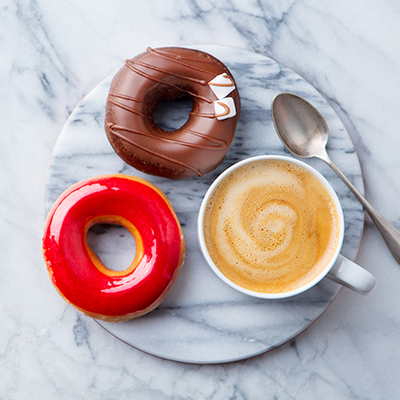 Coffee with donuts on marble table background. Copy space. Top view.