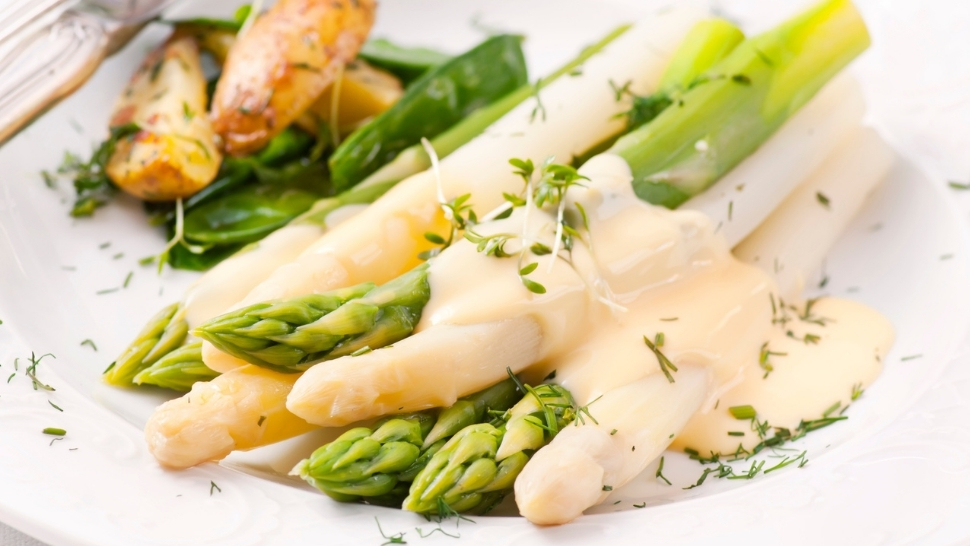 green and white asparagus with hollandaise sauce on top
