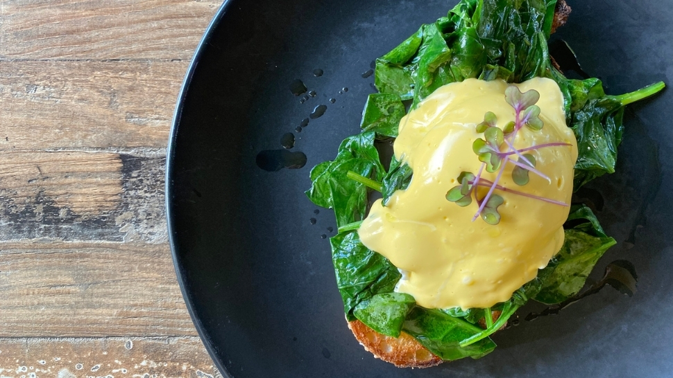 eggs florentine on a blue plate on a wood table