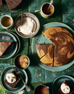 Marble cake and creamy coffee on earthy green plates with dollops of whipped topping.