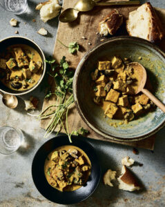 Plant-based curry with tofu and mushrooms highlights sustainable, home-cooked nourishment.