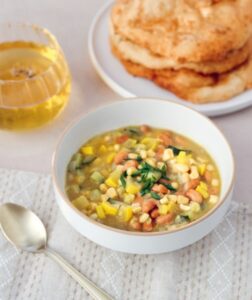 Hearty bowl of corn and bean soup served with golden frybread and tea.